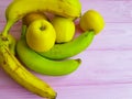 Green banana and yellow apples on a pink wooden, harvest Royalty Free Stock Photo