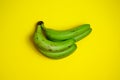 Green bananas on yellow background.  Ugly food concept. Minimalism concept. Royalty Free Stock Photo