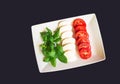 Green basil leaves, mozzarella cheese and ripe tomatoes in form and color of italian flag on dark background. Royalty Free Stock Photo