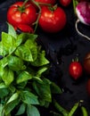 Green basil and tomatoes on a branch, cherry tomato, radishes and green pea pods on a dark background