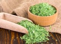 Green bath salt in spoon and burlap on wooden surface . Royalty Free Stock Photo
