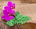 Green bath salt in spoon on wooden surface and Orchid. Royalty Free Stock Photo