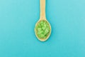 Green bath salt in a wooden spoon on a blue background. Minimalism Royalty Free Stock Photo