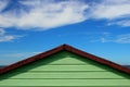 A green beach hut against a bright blue sky