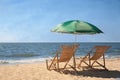 Green beach umbrella and deck chairs on sandy seashore Royalty Free Stock Photo