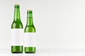 Green beer bottles longneck 500ml and 330ml with blank white label on white wooden board, mock up.