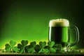 Green beer with foam on top, surrounded by clover leaves, on a wooden table