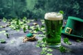 Green beer pint and leprechaun hat over dark green background, decorated with shamrock leaves Royalty Free Stock Photo