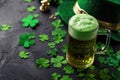 Green beer pint and leprechaun hat over dark green background, decorated with shamrock leaves Royalty Free Stock Photo