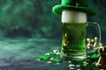 Green beer pint and leprechaun hat over dark green background, decorated with shamrock leaves Royalty Free Stock Photo