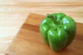 Green bell pepper with water droplets isolated on the wooden cutting board Royalty Free Stock Photo