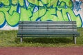 Green bench with graffiti on the background