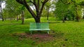 Green bench in the fresh green park standing by a tree in beautiful big park Royalty Free Stock Photo