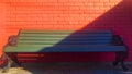 Green bench and red brick wall with oblique shadow. Royalty Free Stock Photo