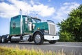 Green classic big rig semi truck tractor driving on the road in Columbia Gorge for pick up loaded semi trailer Royalty Free Stock Photo