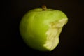 Green bitten apple on dark background Royalty Free Stock Photo