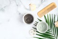 Green and black face clay masks with tropical palm leaf, hair comb, loofah sponge and seashells on marble background. SPA natural Royalty Free Stock Photo