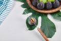 Green and black figs on a ceramic plate with a knife and a leaf Royalty Free Stock Photo