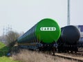 Green and black freight trains in rail yard under grey blurry sky