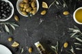 Green and black olives in white bowls next to a bottle with olive oil and leaves on a black background. .Bottle of cold pressed Royalty Free Stock Photo