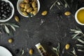 Green and black olives in white bowls next to a bottle with olive oil and leaves on a black background. .Bottle of cold pressed Royalty Free Stock Photo