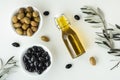 Green and black olives in white bowls next to a bottle with olive oil and leaves on a white background. .Bottle of cold pressed Royalty Free Stock Photo