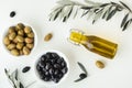 Green and black olives in white bowls next to a bottle with olive oil and leaves on a white background. .Bottle of cold pressed Royalty Free Stock Photo