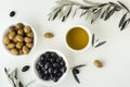 Green and black olives in white bowls next to a bottle with olive oil and leaves on a white background. .Bottle of cold pressed Royalty Free Stock Photo