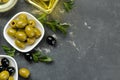 Green and black olives in a white ceramic bowl with leaves on a dark graphite background. top view. space for text Royalty Free Stock Photo