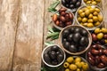 Green, black and red olives, olive oil on a brown wooden background. Royalty Free Stock Photo