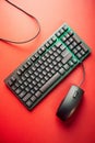 Green and Black Wired Keyboard with a Gray Computer Mouse on a Red Surface technology input device Royalty Free Stock Photo