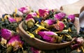 Green blended tea. green tea leaves with dried rose flowers in a wooden spoon isolated on white.