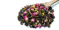 Green blended tea. green tea leaves with dried rose flowers in a wooden spoon isolated on white.