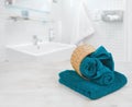Green-blue folded towels in wicker basket over defocused bathroom