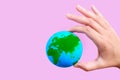 Green and Blue Globe in Hand on Pink Royalty Free Stock Photo