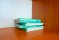 Green and blue notebooks on a wooden shelf in the closet. stack of thin notebooks Royalty Free Stock Photo