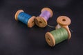 green blue purple white bobbins threads on black skin