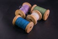 Green blue purple white bobbins threads on black skin