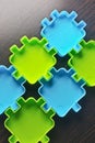 Green and blue puzzle like toys on a brown wooden background. Royalty Free Stock Photo