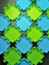 Green and blue puzzle like toys on a brown wooden background. Royalty Free Stock Photo