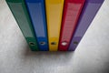 A green, blue, yellow, red and purple binder standing side by side on a grey floor. The concept of work, accounting Royalty Free Stock Photo