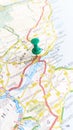 A green board pin stuck in Dundee on a map of Scotland portrait