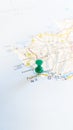 A green board pin stuck in Paphos on a map of Cyprus portrait