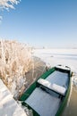 Green boat on ice in winter landscape