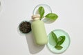 Advertising scene with a bottle mockup for cosmetic with green tea leaves on beige background Royalty Free Stock Photo