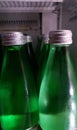 Green bottles of water same size in the refrigerator