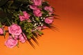 Green bouquet with small roses on an orange background. Pink small roses Royalty Free Stock Photo