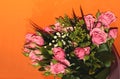 Green bouquet with small roses on an orange background. Pink small roses Royalty Free Stock Photo