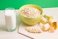 green bowl with dry oatmeal, staak of milk and sliced banana on wooden table Royalty Free Stock Photo