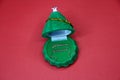 Green box in the form of a Christmas tree with earrings inside on a red background